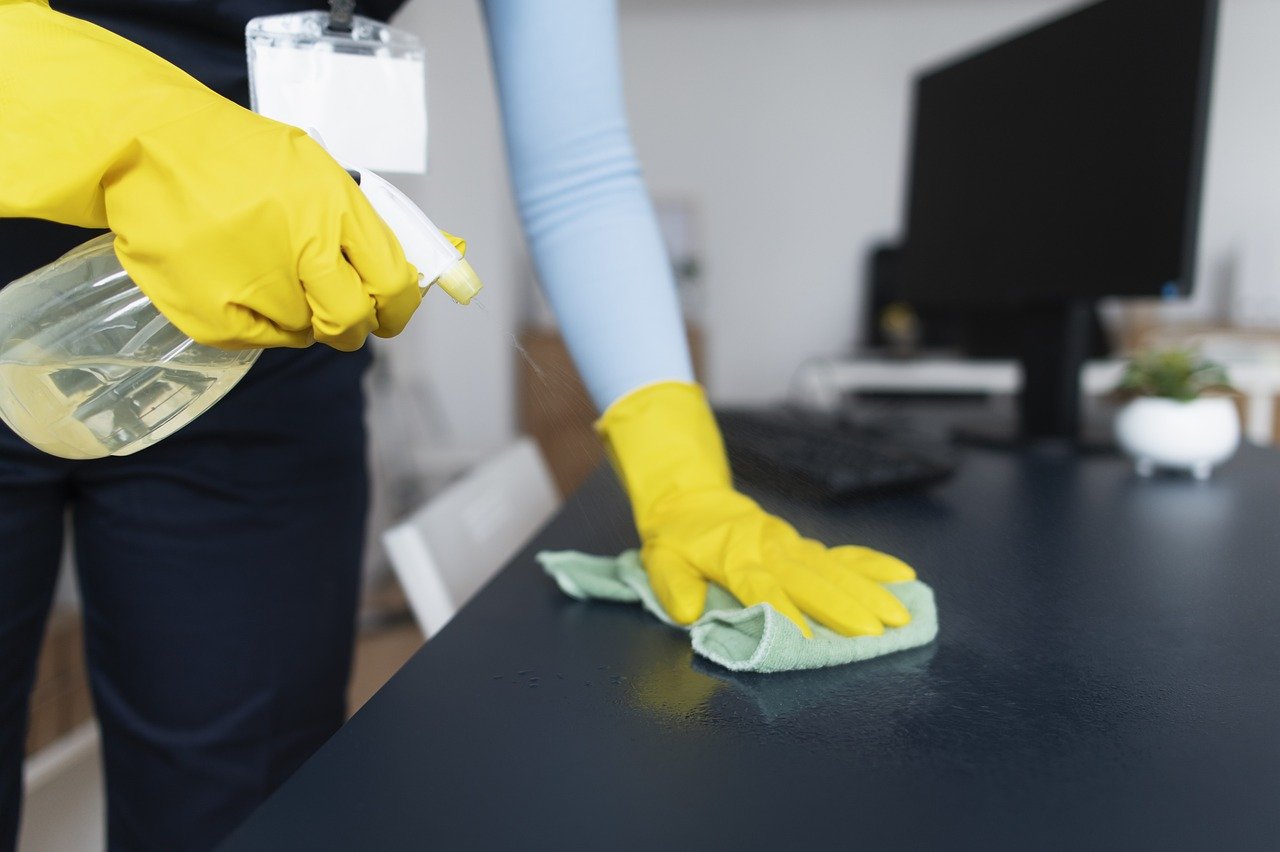 Persona desinfectando una mesa de oficina